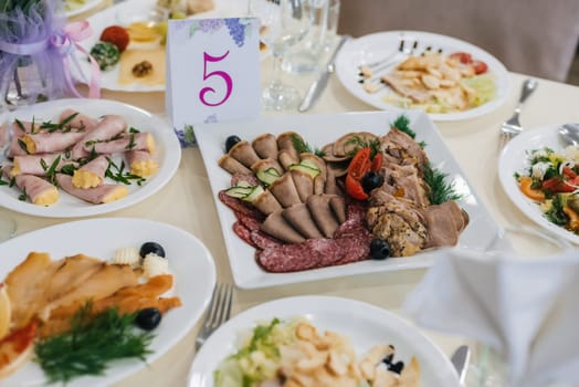 various meat snacks and salads on the festive table for dinner in the restaurant