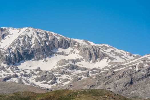 The lush green Sobucimen plateau in spring and the mountains with some melted snow behind.