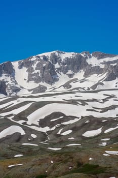 The lush green Sobucimen plateau in spring and the mountains with some melted snow behind.