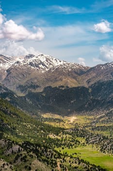 The lush green Sobucimen plateau in spring and the mountains with some melted snow behind.