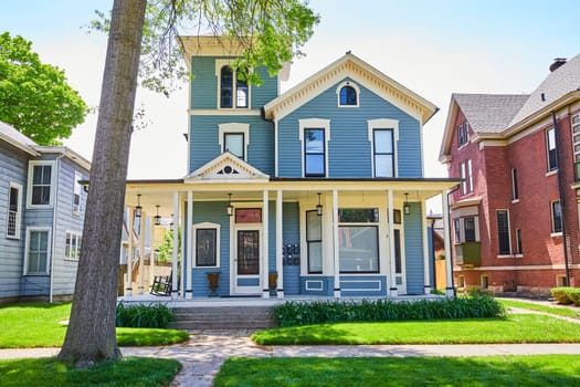 Charming blue suburban home in Fort Wayne, surrounded by lush greenery, embodying American family living.