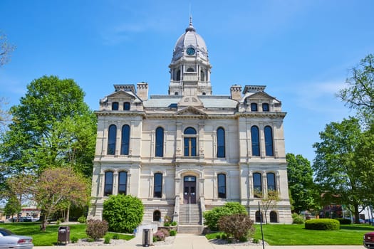 Historic Kosciusko County Courthouse in Warsaw under a clear blue sky, embodying neoclassical grandeur and civic pride.