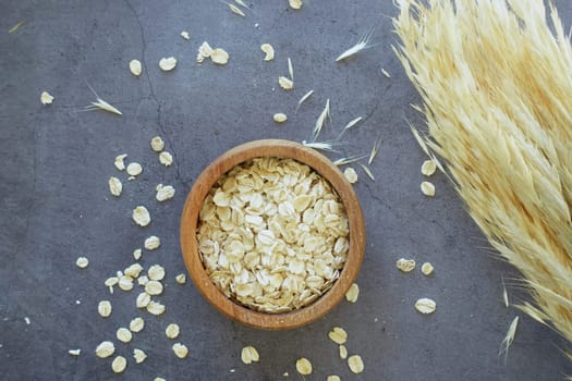 oats flakes in a a wooden bowl on black background .