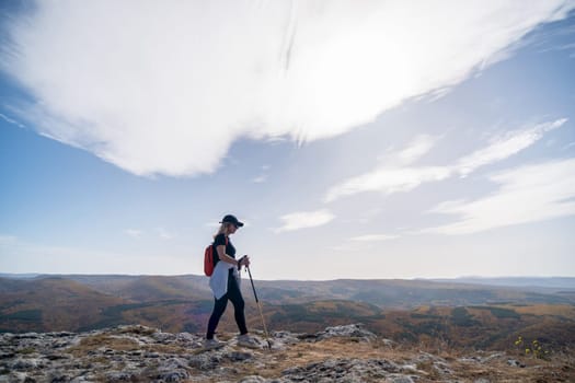 woman on mountain peak looking in beautiful mountain valley in autumn. Landscape with sporty young woman, blu sky in fall. Hiking. Nature.