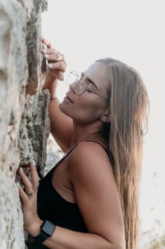 Woman travel sea. Young Happy woman in a long red dress posing on a beach near the sea on background of volcanic rocks, like in Iceland, sharing travel adventure journey