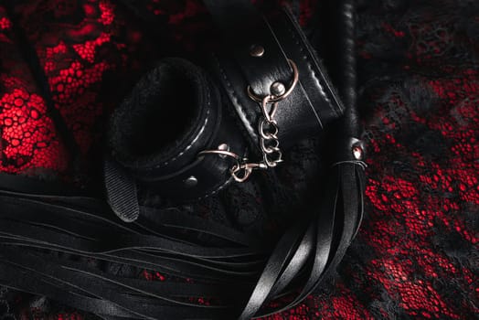 Leather handcuffs and whip for BDSM role-playing sex games on lingerie background