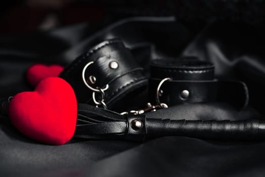 Leather whip and handcuffs as a gift for BDSM for Valentine's day. Concept of domination and submission in passionate hard sex with toys and role-playing games