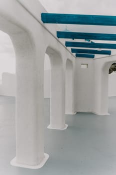 A blue and white building with a blue door sits on a balcony overlooking the ocean. The scene is serene and peaceful