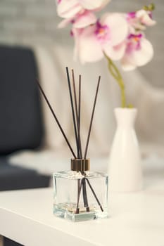 Liquid home perfume in glass diffuser with sticks on chair close up