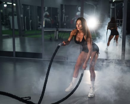 Caucasian woman doing exercise with ropes. Circuit training in the gym