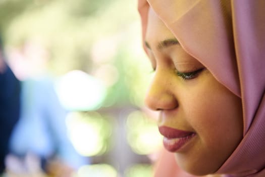 A Middle Eastern girl wearing a hijab, with a bright smile and a pink headscarf, captured in a close-up portrait exuding joy and positivity.