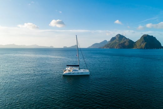 A serene sailboat is anchored in clear, blue tropical waters with picturesque islands in the background.