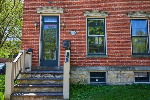 Charming historic brick home in Fort Wayne, bathed in sunlight, showcasing traditional architecture and lush greenery.