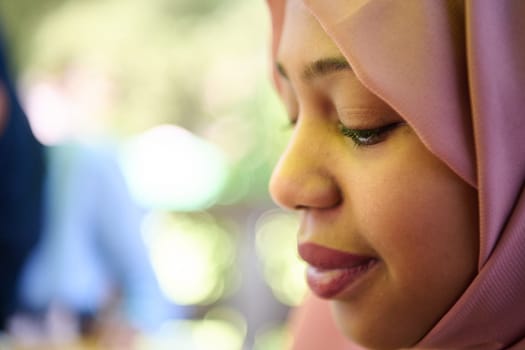 A Middle Eastern girl wearing a hijab, with a bright smile and a pink headscarf, captured in a close-up portrait exuding joy and positivity.