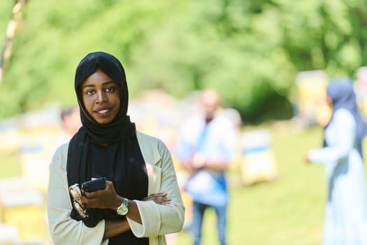 Middle Eastern Muslim woman in a hijab uses a smartphone while managing a small beekeeping business, blending modern technology with traditional practices