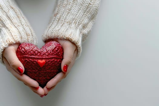 A woman is holding a red heart shaped box with a red ribbon. The woman's hand is holding the box close to her chest, and she seems to be smiling