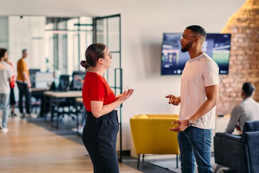 Young business colleagues, including an African American businessman, engage in a conversation about business issues in the hallway of a modern startup coworking center