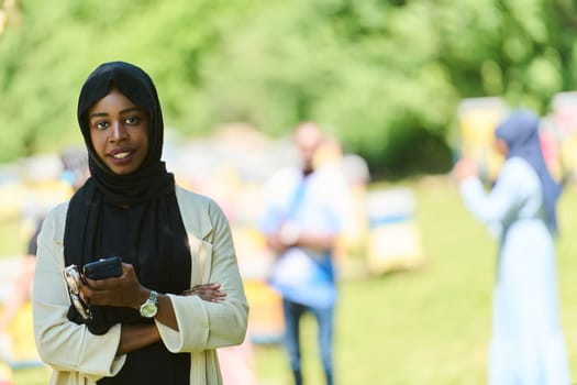 Middle Eastern Muslim woman in a hijab uses a smartphone while managing a small beekeeping business, blending modern technology with traditional practices