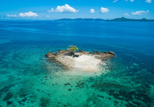 Aerial view of a small tropical island on an atoll with beautiful sandy beach surrounded by coral reef.