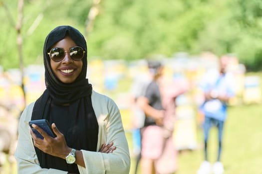 Middle Eastern Muslim woman in a hijab uses a smartphone while managing a small beekeeping business, blending modern technology with traditional practices