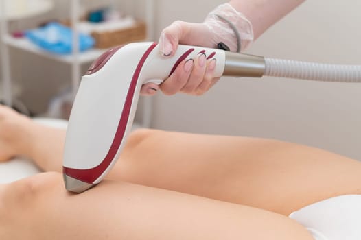 Close-up of laser hair removal on the leg. The doctor removes unwanted hair from the patient with an electric device.