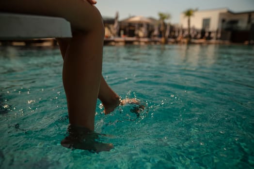 A charming woman in a bikini sits by the poolside, her back resting against the edge. High quality photo