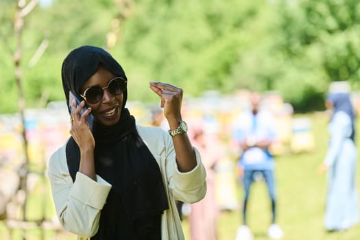 Middle Eastern Muslim woman in a hijab uses a smartphone while managing a small beekeeping business, blending modern technology with traditional practices