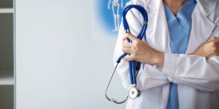 Confident healthcare professional holding stethoscope in medical office.