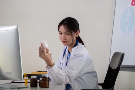 Asian Female Doctor Examining Medication Bottle in Medical Office.