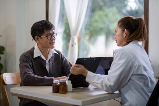 Senior east asian man discussing health with female doctor indoors.