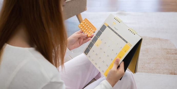 A young woman with a birth control pills reads instructions on how to use them correctly..