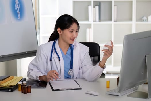 Asian Female Doctor Analyzing Medication Bottle in Clinic.