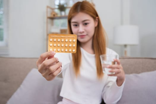 A young woman with a birth control pills reads instructions on how to use them correctly..