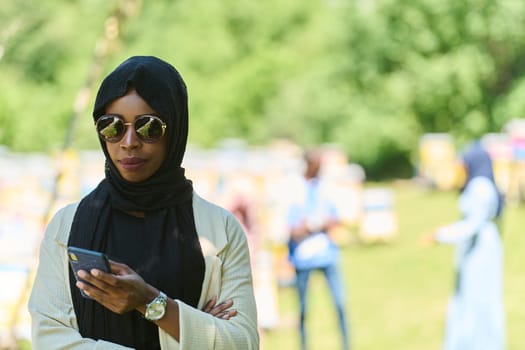Middle Eastern Muslim woman in a hijab uses a smartphone while managing a small beekeeping business, blending modern technology with traditional practices