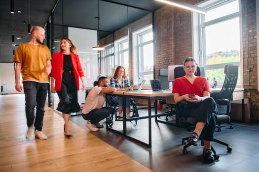 A diverse group of business professionals collaborates in a modern startup coworking center, utilizing a mix of paper-based and technological tools such as mobile phones and computers .