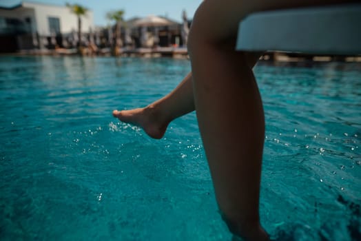 A radiant young lady in a swimsuit relaxes by the pool, facing away from the water. High quality photo