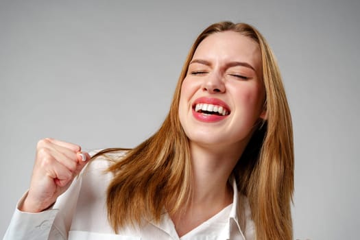 Joyful Young Blonde Woman Smiling against gray background in studio