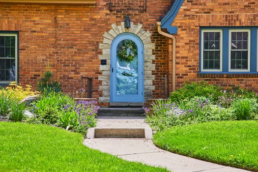 Charming suburban home in Fort Wayne with a vibrant garden and stylish blue door, perfect for family life.