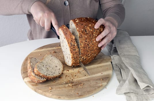 Freshly baked bread on a cutting board. Woman cutting bread.