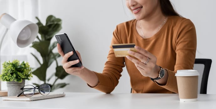 Happy young woman is shopping online and paying with credit card using online banking application..