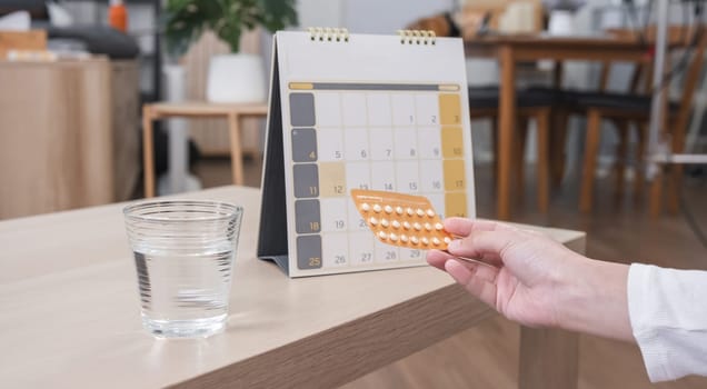 Close-up, Young woman hands holding a birth control pill pack and a calendar to check when to take the pills..