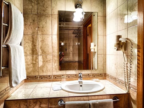 Modern bathroom interior with sink and mirror. Elegant marble bathroom featuring a sink and lit wall mirror