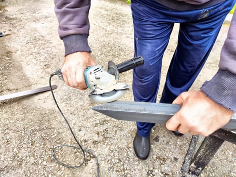 Craftsman Cutting Metal Column With Grinder Outdoors. Man using a grinder on metal column, creating sparks