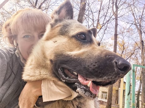 Adult girl or middle aged woman with shepherd dog in an autumn day