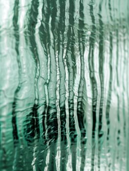 Macro shot of a glass pane with a frozen texture effect and a blend of turquoise and white hues.