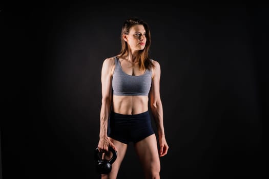 Attractive young athlete with a muscular body exercising crossfit workout with kettlebell.