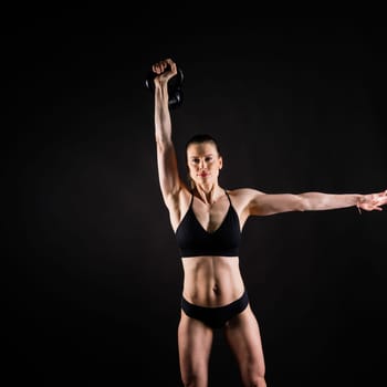 Attractive young athlete with a muscular body exercising crossfit workout with kettlebell.