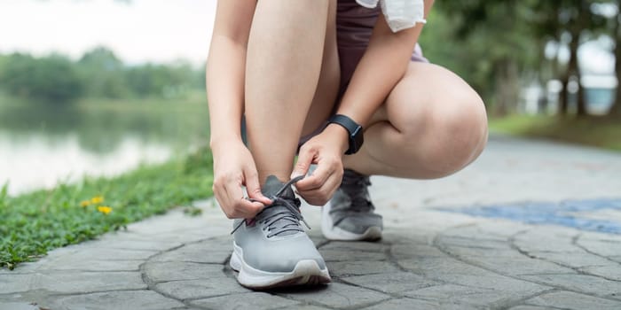 Young woman tying shoelace in the park. Sport and fitness concept.