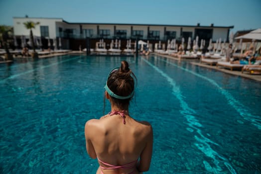 A stunning lady in a bikini reclines by the poolside, her back turned to the water. High quality photo