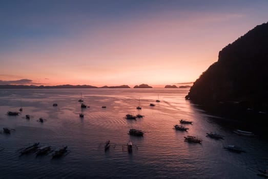 Aerial view of boats and yachts in the tropical bay on the sunset. El Nido, Palawan, Philippines. Travel concept.